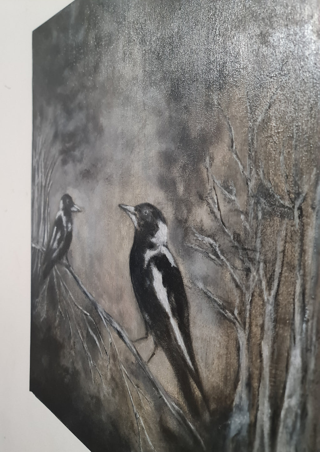 A textured painting of two black-and-white birds perched on bare tree branches against a smoky gray-brown background.