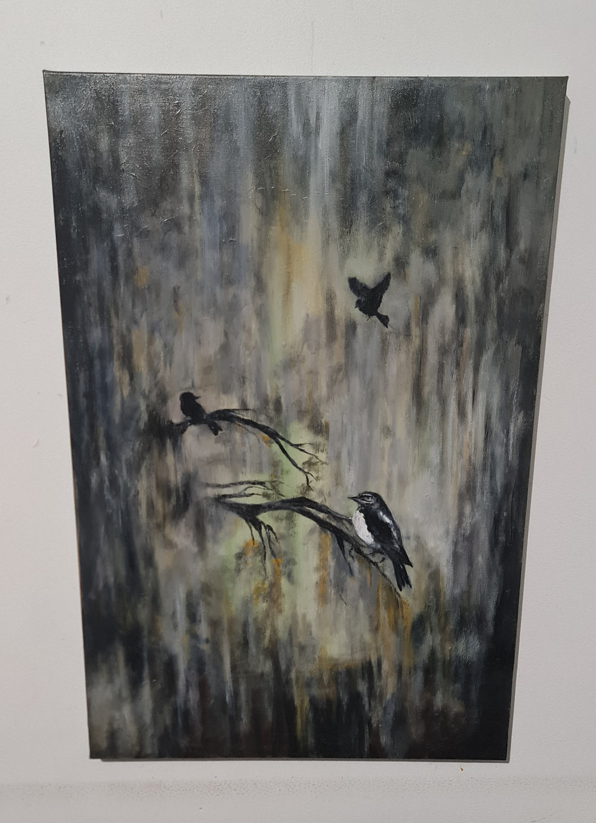 An abstract painting of three birds in black and white perched on branches against a textured gray, black, and beige background, displayed on a white wall.
