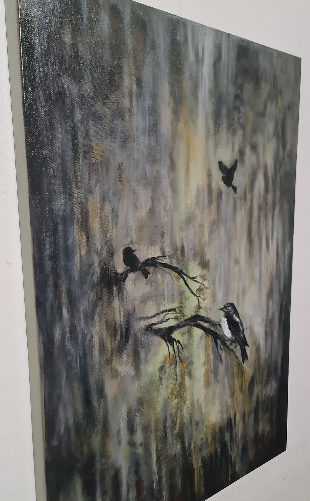 An abstract canvas painting featuring three black birds perched on and flying above a textured, vertical brushstroke background in shades of gray, black, and muted gold.