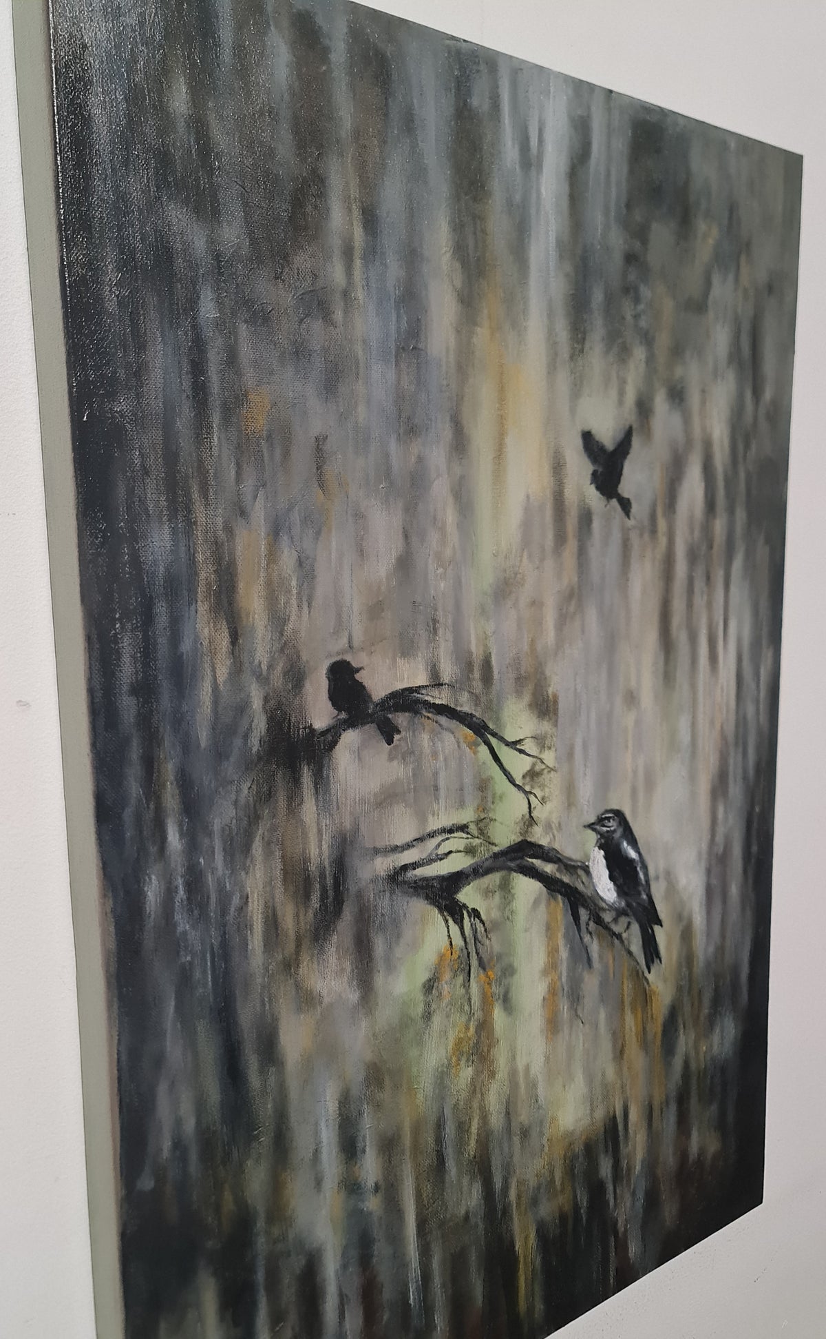 An abstract canvas painting featuring three black birds perched on and flying above a textured, vertical brushstroke background in shades of gray, black, and muted gold.