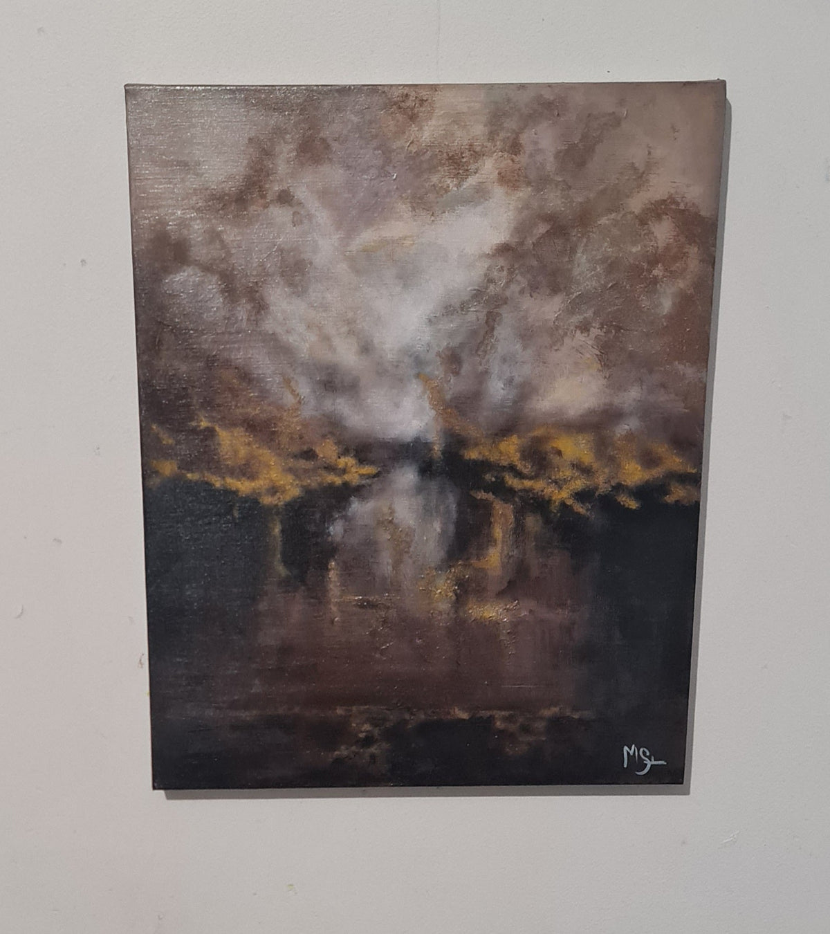 An abstract landscape painting on canvas depicting a dramatic sky with dark clouds, golden light, and reflections on water, hung on a light gray wall.